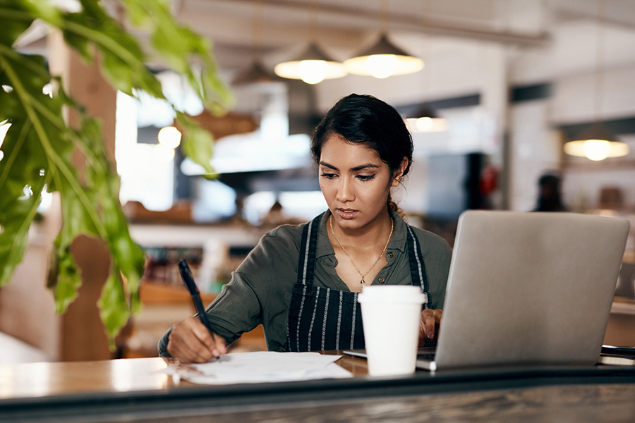 Photograph of a female cafe owner using a laptop