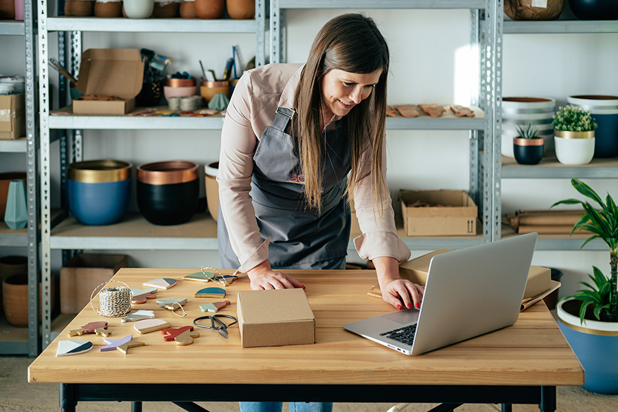 A woman using a laptop in her shop of creative homewares