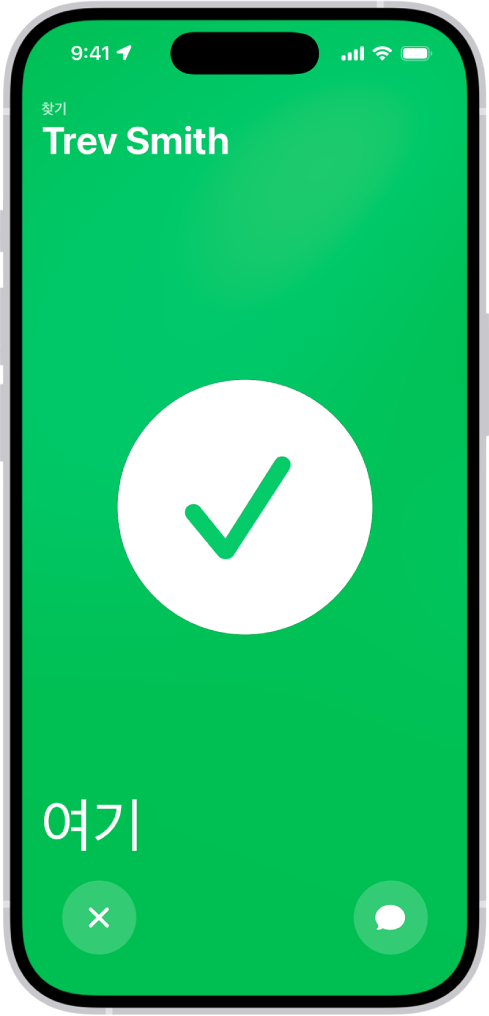 iPhone 화면이 녹색 배경이고 중앙에 큰 체크 표시가 있음. 왼쪽 상단 모서리에 찾는 사람의 이름이 있고 왼쪽 하단 모서리에는 친구와 만났음을 알리는 ‘여기’라는 단어가 표시되어 있음.
