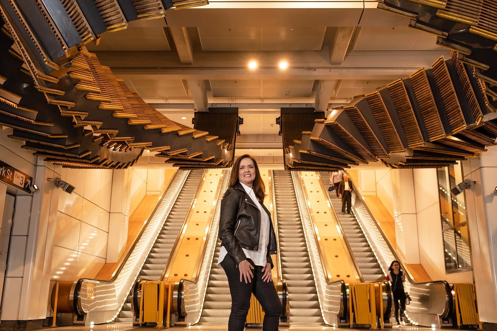 Debra Taylor, COO of OpenSparkz, at Wynyard Station standing beneath Chris Fox's 'Interloop' sculpture (supplied)