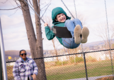 Woman pushing kid on swing