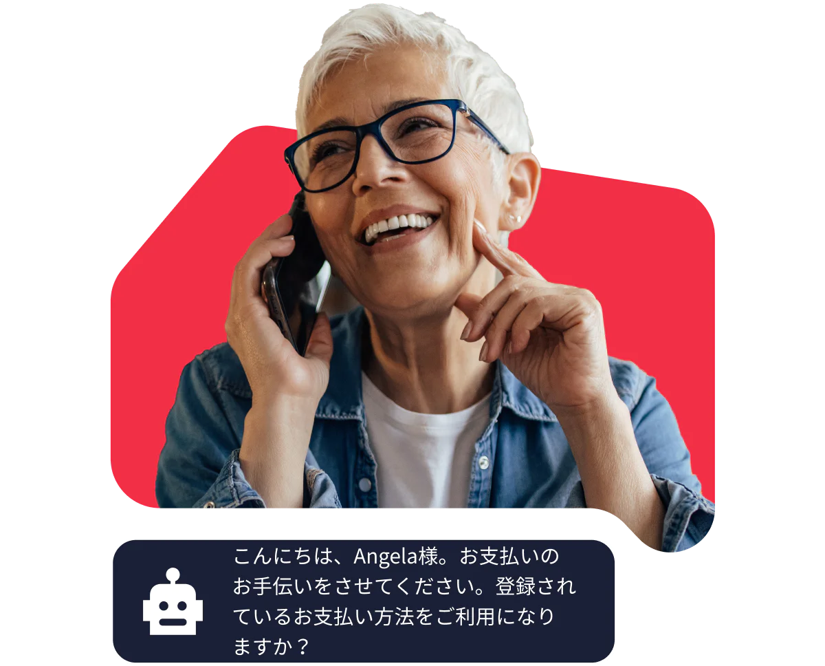 Elderly woman with glasses smiling while talking on the phone against a red background.