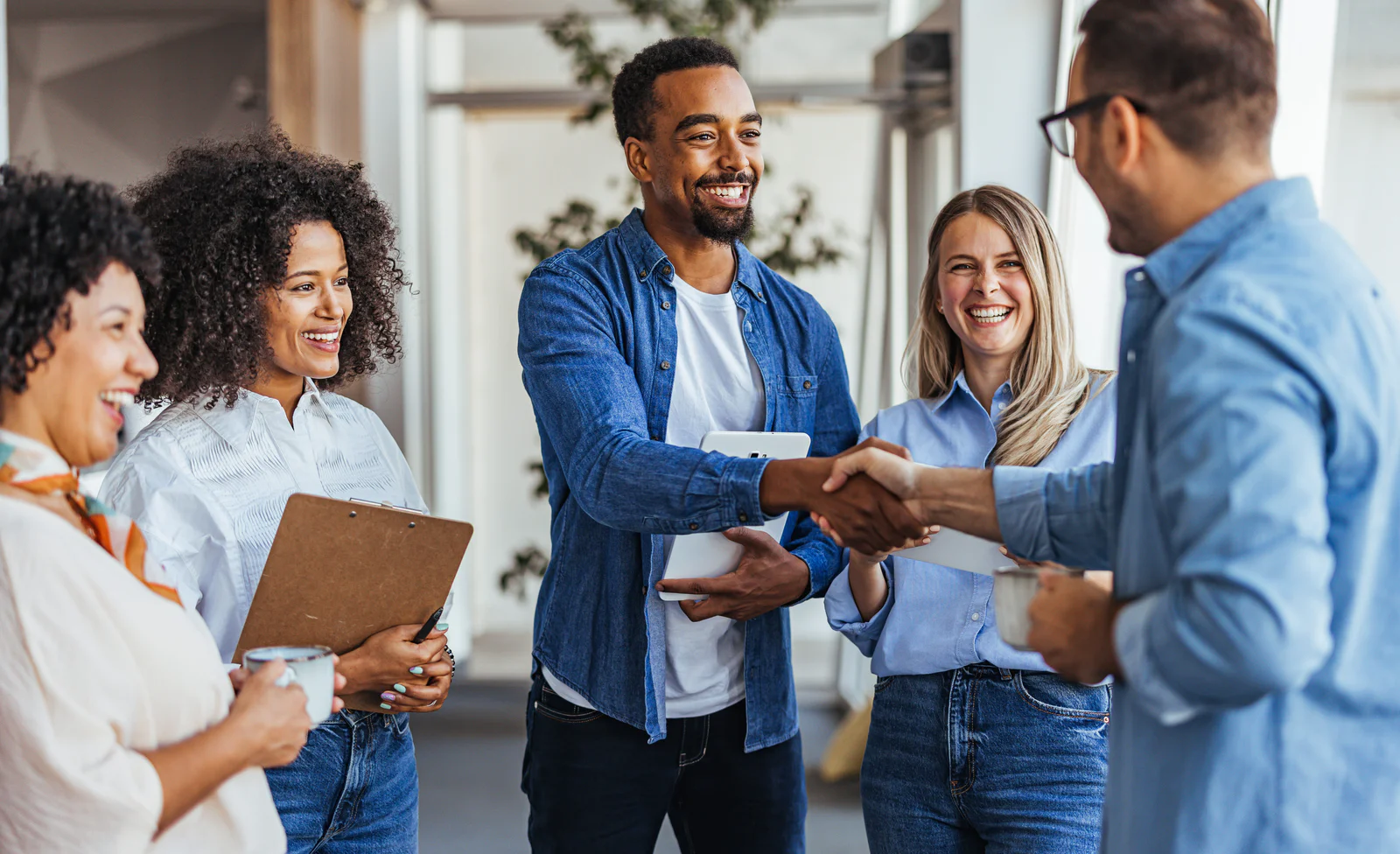 Colleagues smiling and shaking hands in a modern office environment.