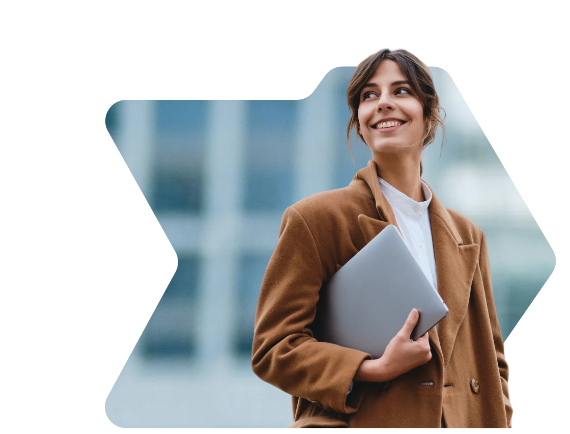 Woman in brown coat smiling and holding a laptop with a birthday discount notification from OWLCLOTHES