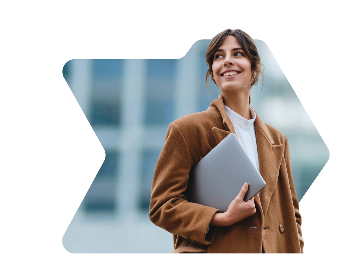 Woman in brown coat smiling and holding a laptop with a birthday discount notification from OWLCLOTHES